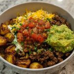 A delicious Loaded Potato Taco Bowl filled with crispy potatoes, seasoned ground beef, pico de gallo, guacamole, cheese, and sour cream.