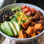 A vibrant and healthy Sweet Potato Taco Bowl filled with roasted sweet potatoes, black beans, corn, avocado, and tomatoes.