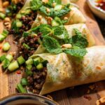 Close-up of delicious Thai Basil Beef Rolls filled with seasoned ground beef, cucumber, and mint, garnished with peanuts.