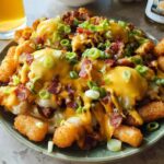 A plate of Ultimate Breakfast Poutine topped with creamy hollandaise sauce, bacon, and green onions.