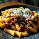A close-up of a bowl of Creamy High Protein Beef Pasta, topped with grated cheese and parsley.