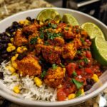 A vibrant Easy Street Corn Chicken Bowl filled with rice, black beans, corn, seasoned chicken, salsa, and lime wedges.