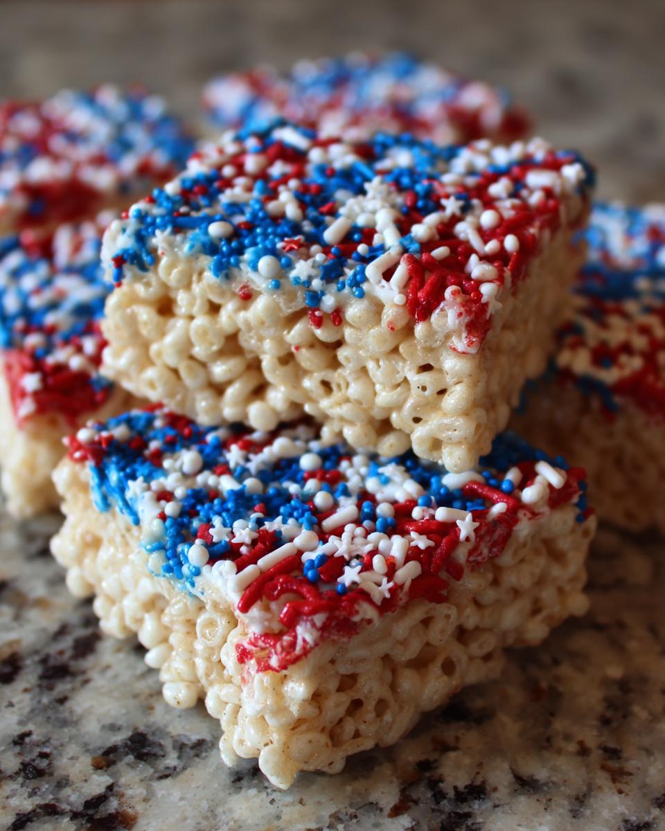 Close-up of Firecracker Rice Krispie Treats decorated with red, white, and blue sprinkles for Fourth of July.