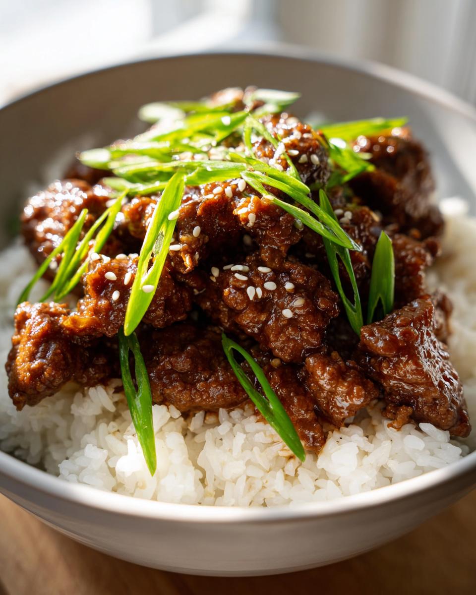 A close-up of a Korean Ground Beef Bowl, featuring tender beef in a savory sauce served over white rice and garnished with sesame seeds and green onions.