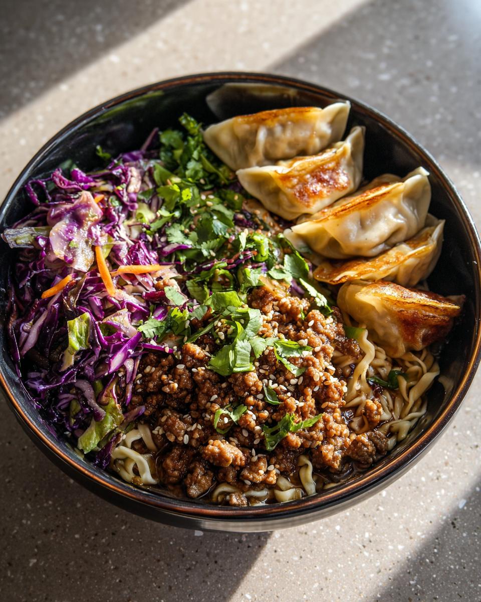 A delicious Potsticker Noodle Bowl with pork, cabbage slaw, noodles, and dumplings, garnished with cilantro and sesame seeds.
